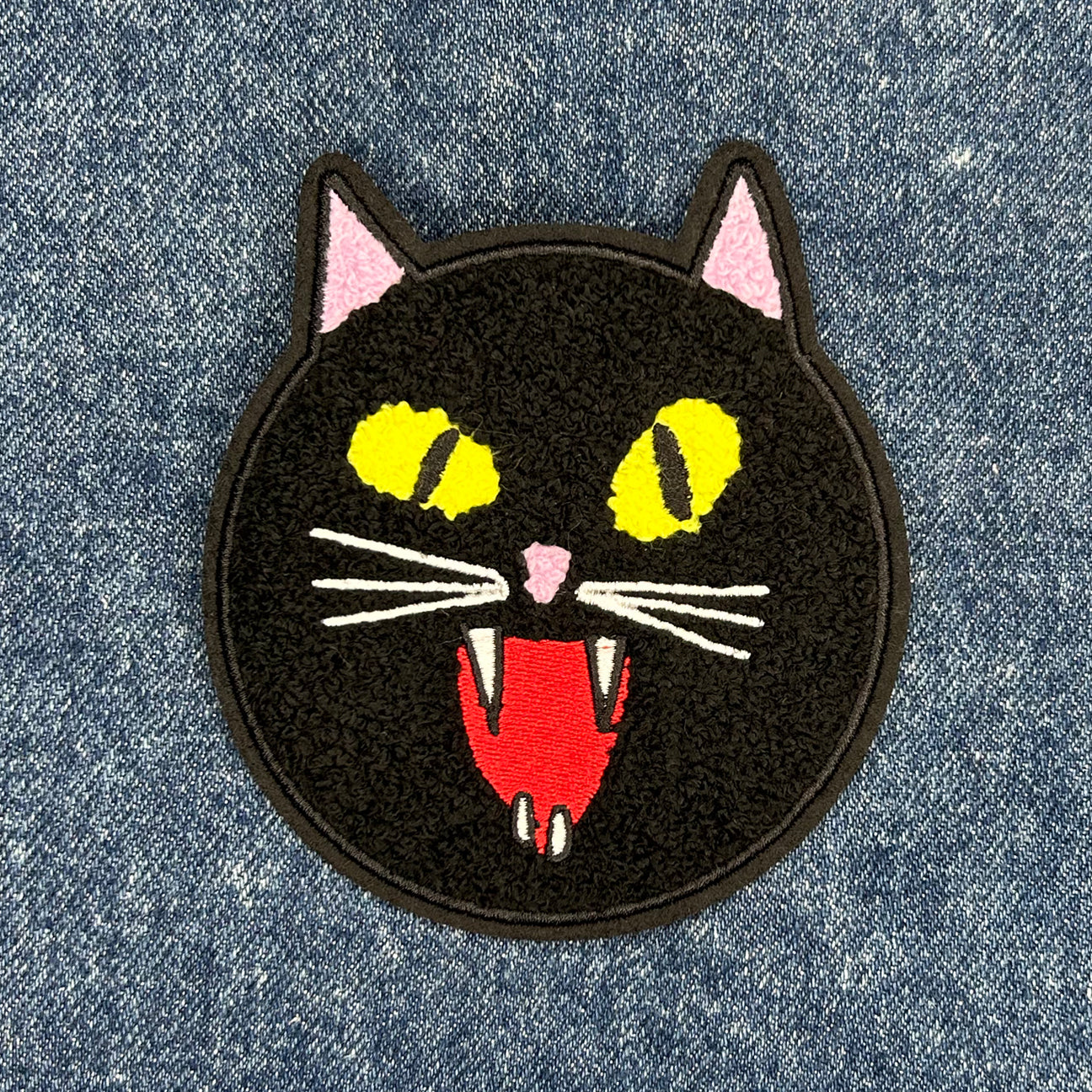 black fuzzy cat chenille patch with yellow eyes and fangs.